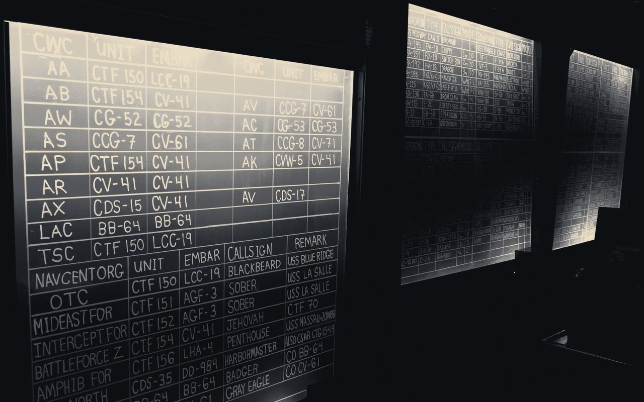 Tablero de información analógico, con filas de datos apenas legibles en la penumbra.